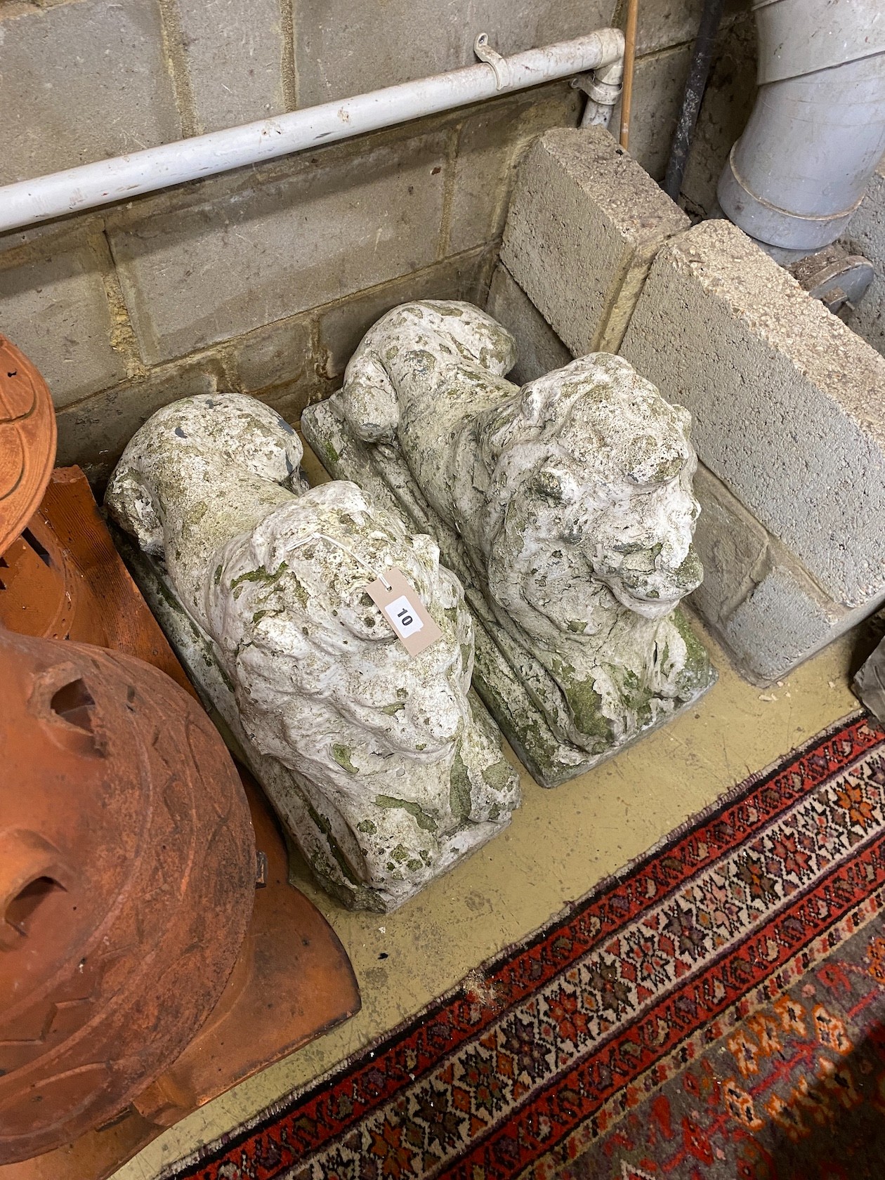 A pair of reconstituted stone recumbent lion garden ornaments, length 70cm, height 50cm, 29cm width